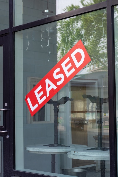 Window of a restaurant with a sign on it saying "leased" in a commercial lease