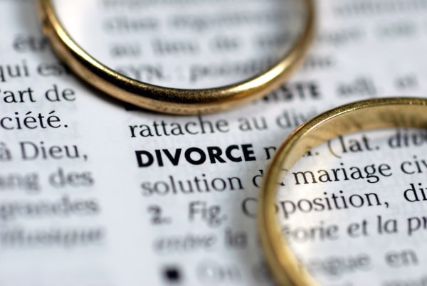 Two wedding rings sitting on a dictionary opened at the page defining divorce