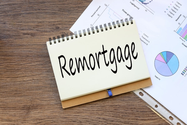 Spiral notepad sitting on a table with the word Re-mortgage written on it wiht soem charts also sitting on the table