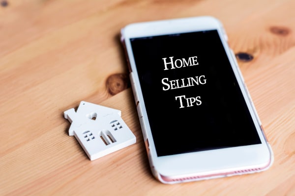 Tablet PC with the words Home Selling Tips showin on it sitting ona table alongside a wooden cutout of a house as we discuss Selling a house over Christmas in Scotland