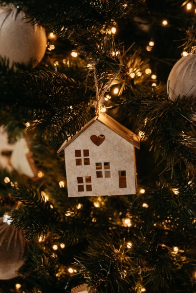 A model wooden house hanging from a Christmas Tree as we answer questions about selling your house at Christmas