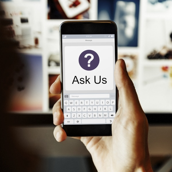 A hand holding a phone with a Question Mark in a Circle with the Words "Ask Us" printed below as we provide answers to making a Will and Power of Attorney in Scotland