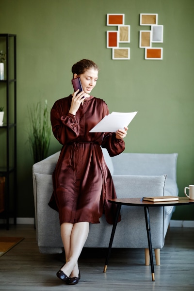 Woman on the phone asking questions on the Cohabitation Agreement Scotland that's she's holding in her hand