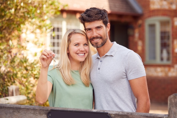 Couple holding keys to a new home bought before selling their previous house in Scotland